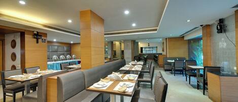 Un restaurante moderno con mesas largas, asientos acolchados y un interior luminoso.