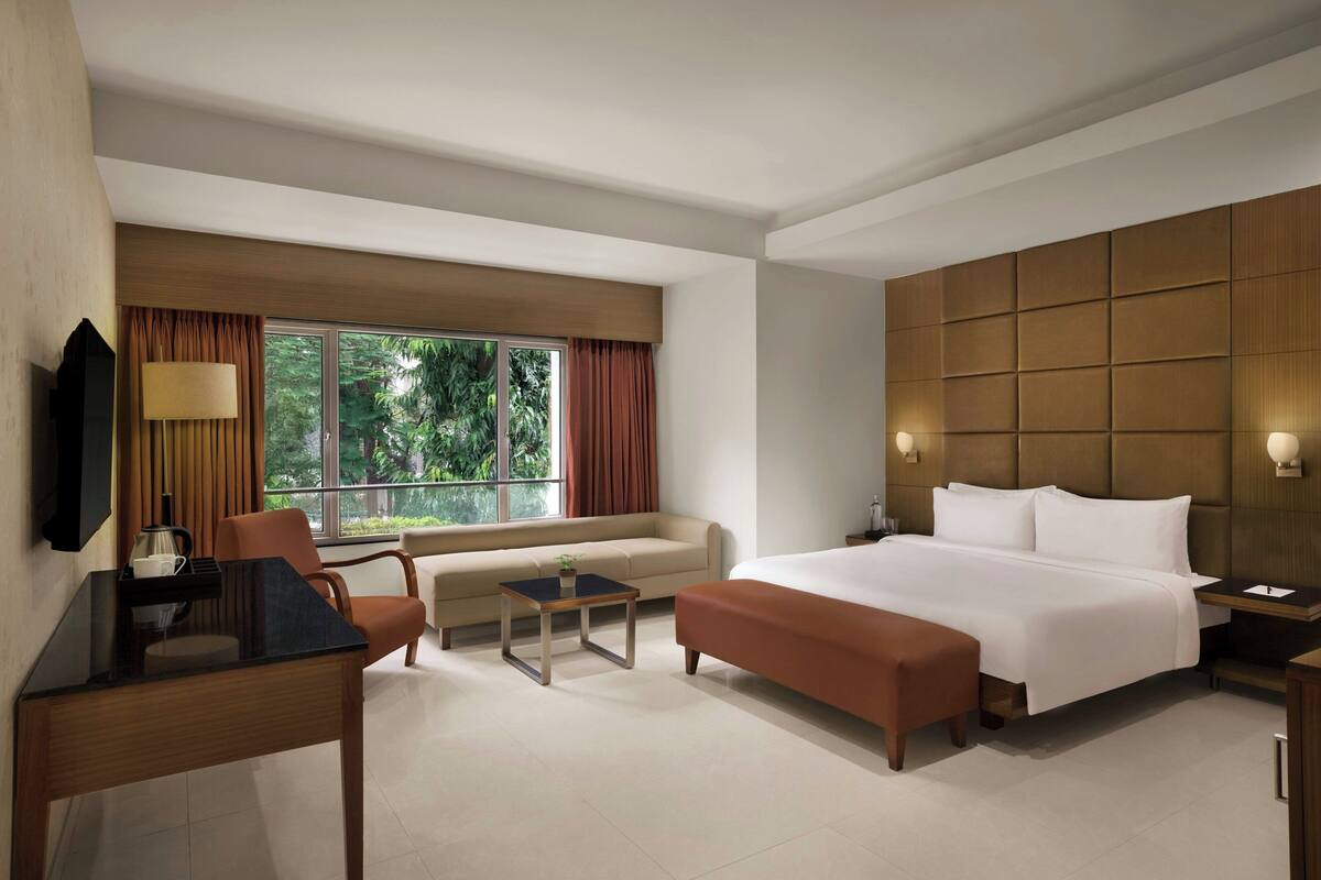 Ein Hotelzimmer mit Bett, einer Sitzecke, einem Schreibtisch und einem Fernseher.