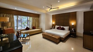 A modern hotel room with a bed, sofa, and desk. - The Fern Residency Pune, Woodland, Series by Marriott (Pune)