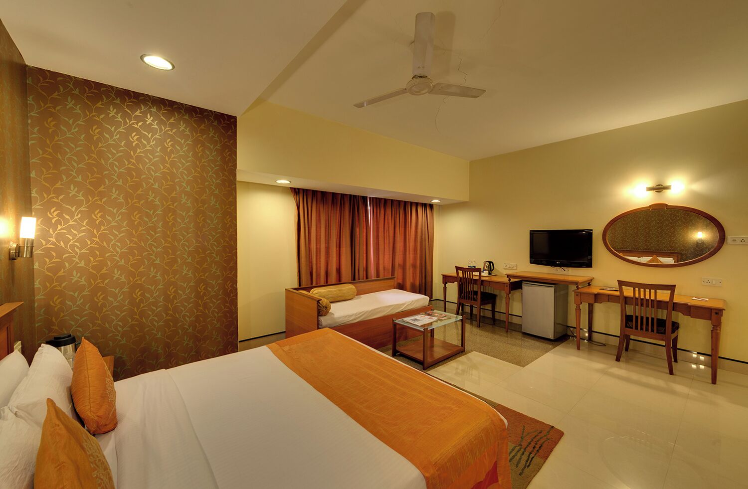 A hotel room with a bed, desk, chair, TV, and a ceiling fan.