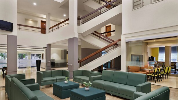 A spacious lobby with multiple seating areas, a staircase, and a dining area. - The Fern Residency Pune, Woodland, Series by Marriott (Pune)