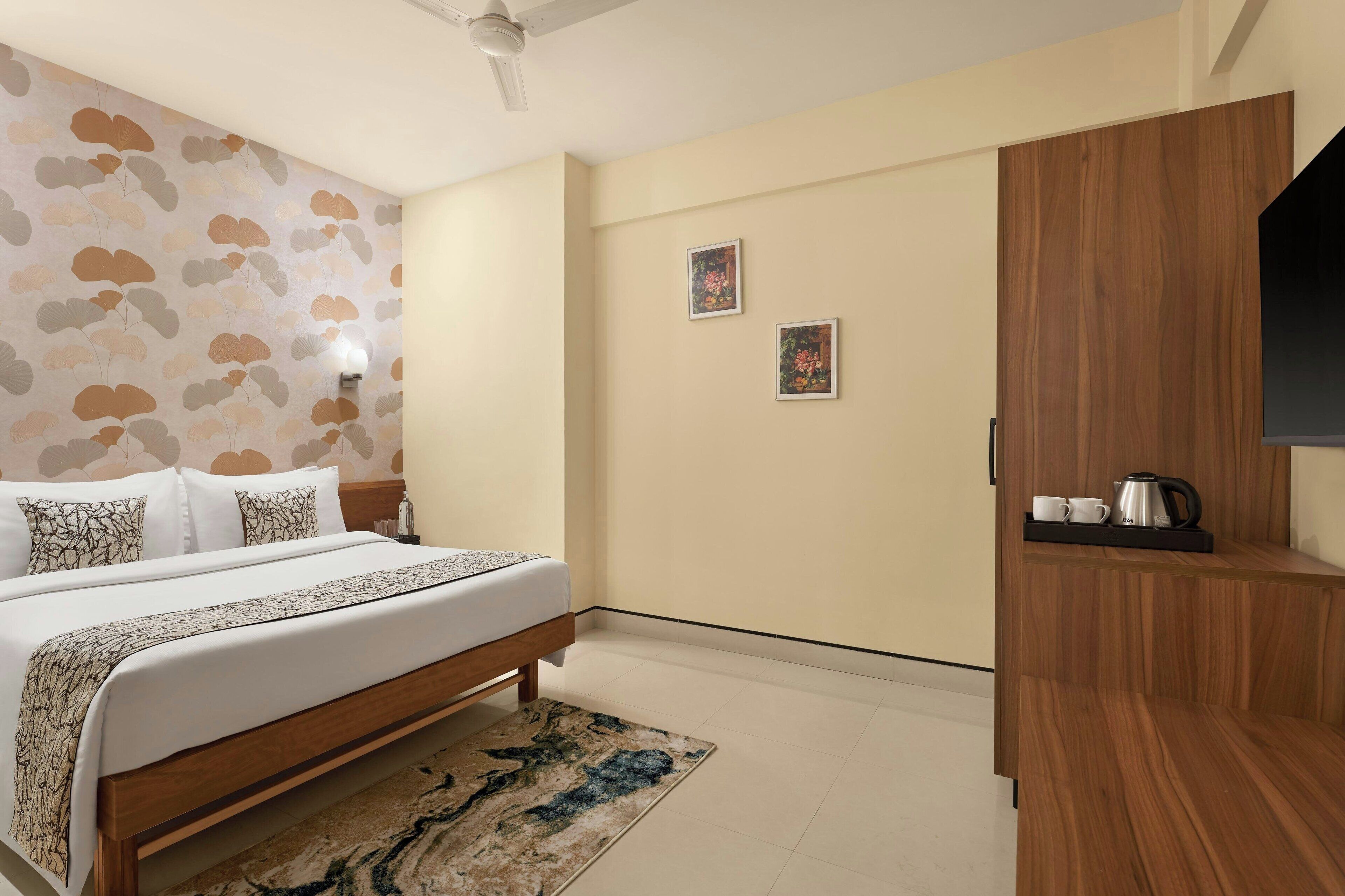 Une chambre d’hôtel avec un lit, une armoire en bois, une table basse et deux tableaux encadrés accrochés au mur.