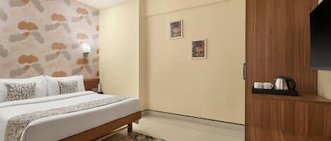 Habitación de hotel con cama, armario de madera, una mesita de centro y dos cuadros en la pared.