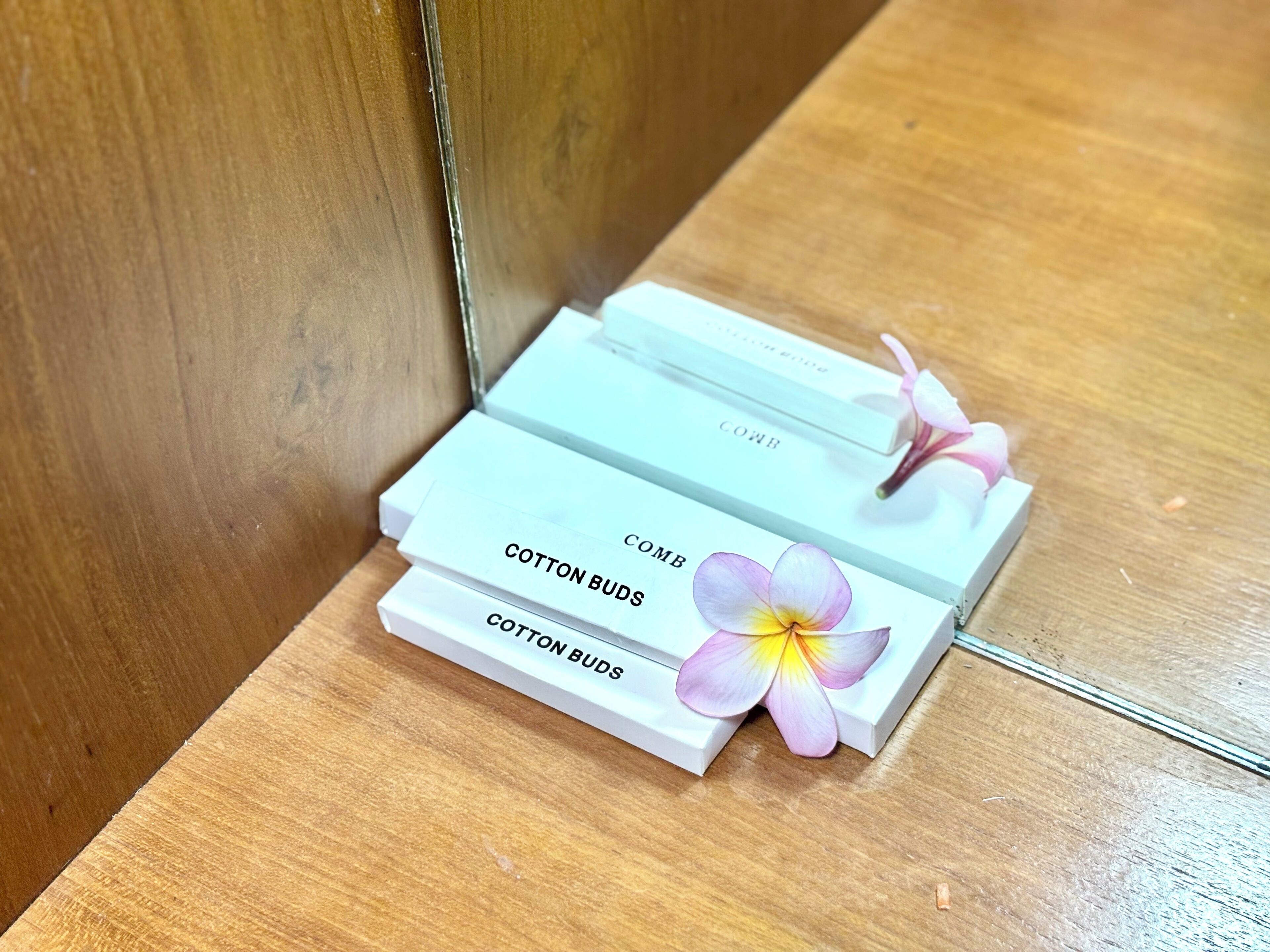 Tres cajas blancas con la etiqueta "COTTON BUDS" apiladas sobre una superficie de madera.