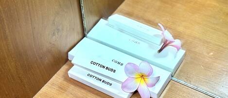 Tres cajas blancas con la etiqueta "COTTON BUDS" apiladas sobre una superficie de madera.