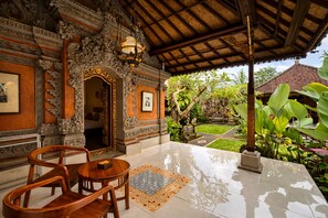 An ornate interior with a tiled floor, wooden furniture, and a thatched roof. - Puri Anyar Ubud by Puri Signatures (Ubud)