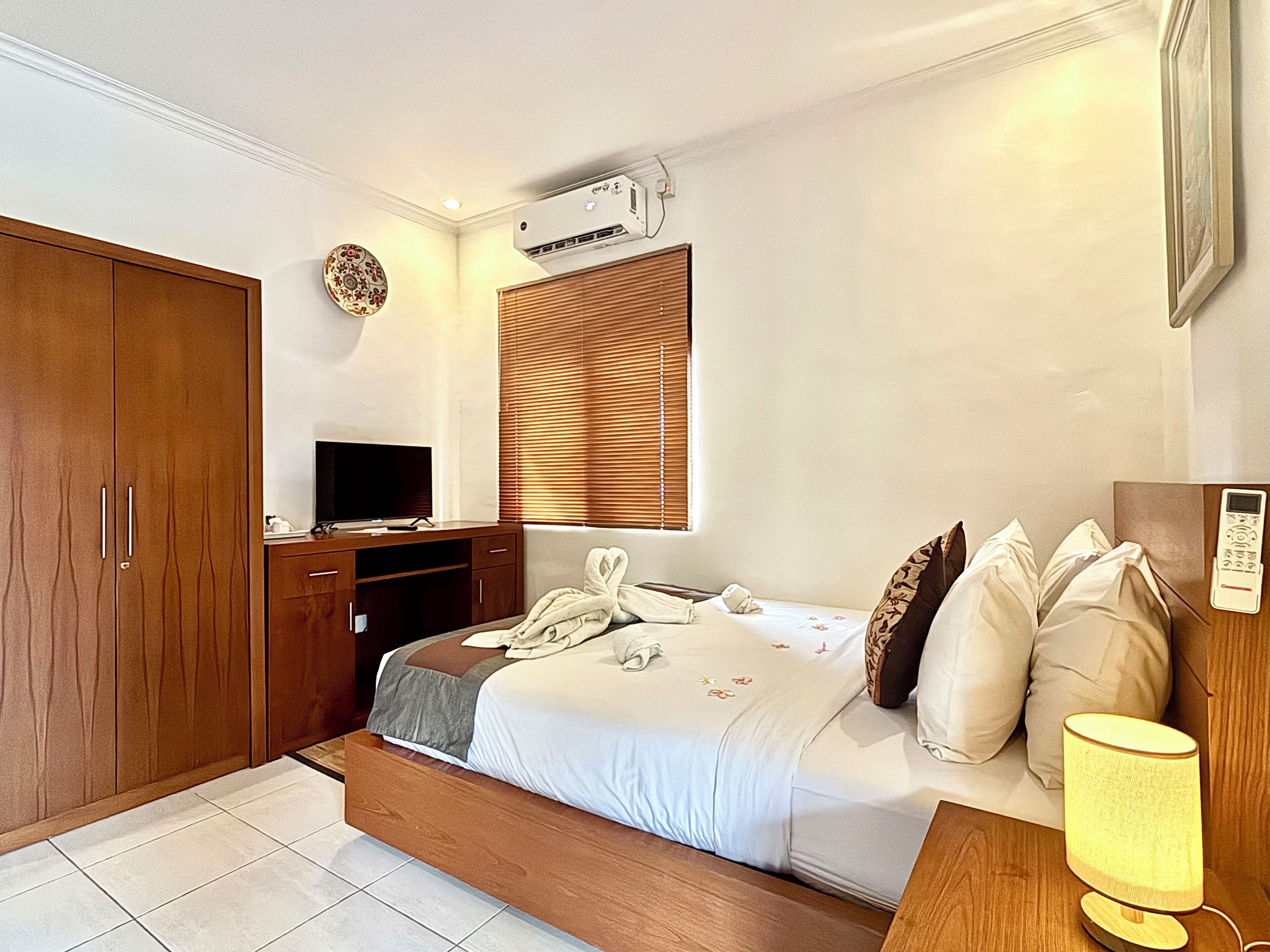 A bedroom with a bed, a TV, a desk, and a wardrobe.