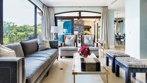 A modern living room with a sofa, armchairs, a coffee table, and a zebra-patterned ottoman. - Villa Essencia in Brasilito (Cabo Velas)