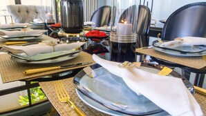 A dining table set with plates, cutlery, and a vase of yellow flowers. - Villa Essencia in Brasilito (Cabo Velas)