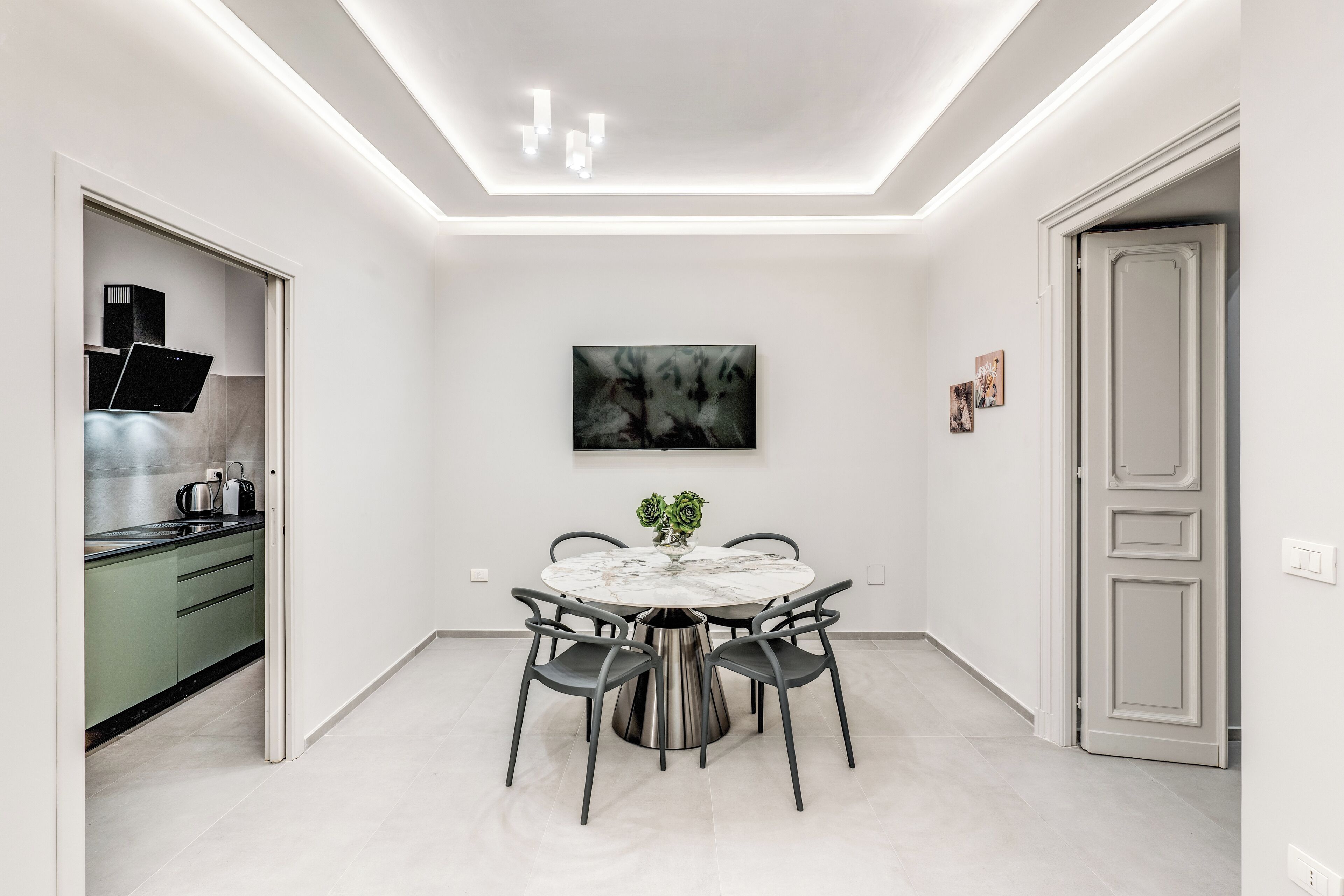 Een moderne eetruimte met een ronde tafel, stoelen en een bloevas.
