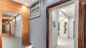 A hallway with a wooden door frame, a mirror, and a wall-mounted decorative piece. - Lady Diamond (Naples)