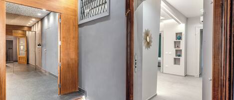 A hallway with a wooden door frame, a mirror, and a wall-mounted decorative piece.