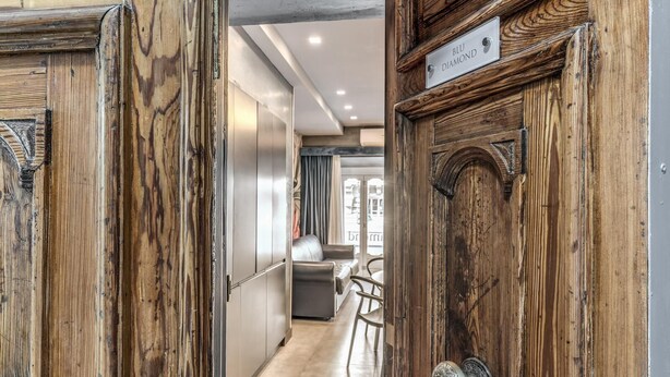 A hallway with wooden doors, a sign reading "BLU DIAMOND", and a view into a dining area with chairs and a table. - Lady Diamond (Naples)