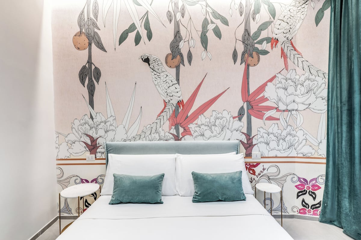 Une chambre à coucher avec un lit, deux oreillers, une table de chevet et une fresque murale.