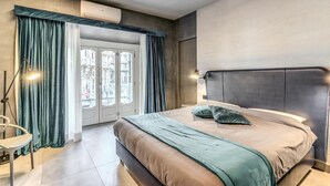 A modern bedroom with a large bed, a view through a glass door, and a ceiling-mounted air conditioning unit. - Lady Diamond (Naples)