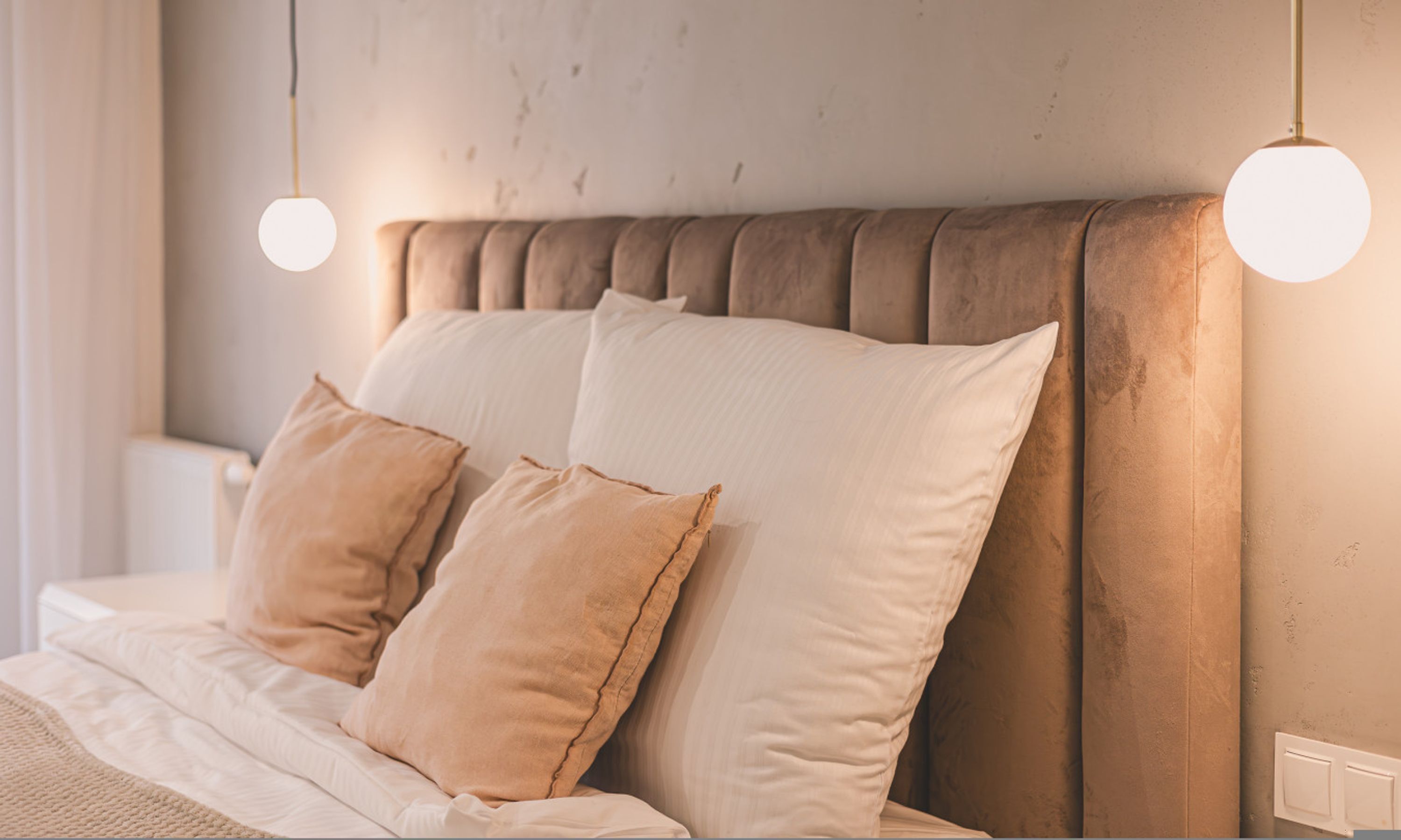 A neatly made bed with a tufted headboard, two bedside lamps, and a bedside table with a lamp.