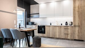 Una cocina moderna con comedor, que cuenta con salpicadero de mármol, armarios de madera y electrodomésticos contemporáneos.