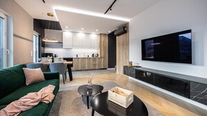 Una sala de estar moderna con un sofá verde, una mesa de centro y un televisor de pantalla plana montado en la pared.