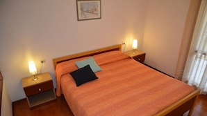 Een slaapkamer met een houten bed, twee nachtkastjes met lampen, een bijzettafeltje en een ingelijste foto aan de muur.