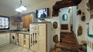 Eine Küche mit Einbauwaschmaschine, einem gro ßen Kühlschrank und einem Fernseher an der Wand.