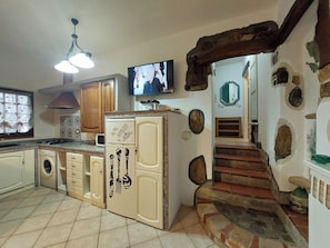 A kitchen with a built-in washing machine, a large refrigerator, and a television on the wall. - Two-room Apartment With Parking Space (Rio)