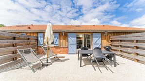 An outdoor patio with a table and chairs, a grill, and a wooden fence. - DOMAINE DU FLAMAND - BRUYÈRE (Naujac-sur-Mer)