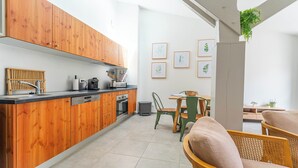 A modern kitchen with wooden cabinets, a dining area with a table and chairs, and framed artwork on the wall. - DOMAINE DU FLAMAND - BRUYÈRE (Naujac-sur-Mer)