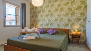 A bedroom with a bed, pillows, a nightstand, a lamp, and a window with curtains. - DOMAINE DU FLAMAND - BRUYÈRE (Naujac-sur-Mer)