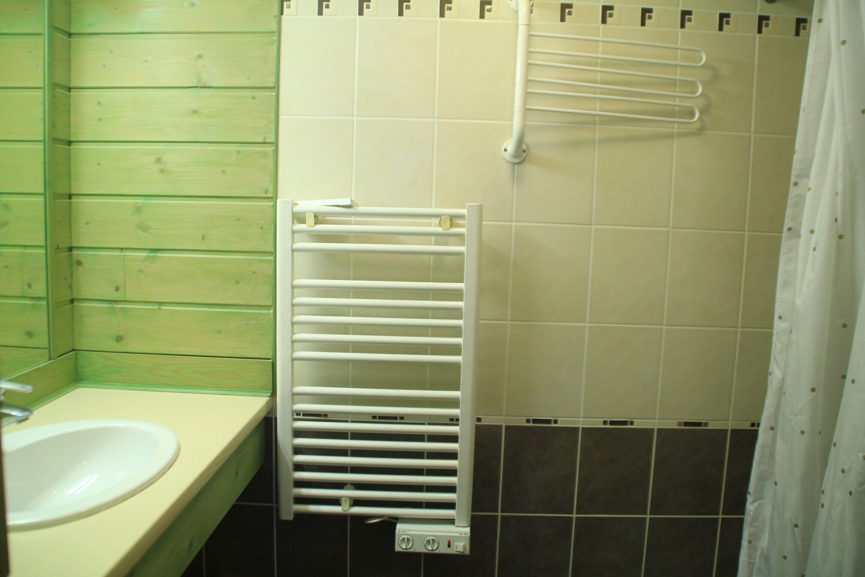 Une salle de bain avec un lavabo blanc, un porte-serviettes et un rideau de douche.