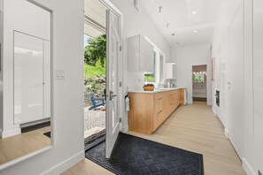 A modern kitchen with a wooden island, white cabinets, and a black doormat. - Walkable to Town and Acadia National Park. (Bar Harbor)