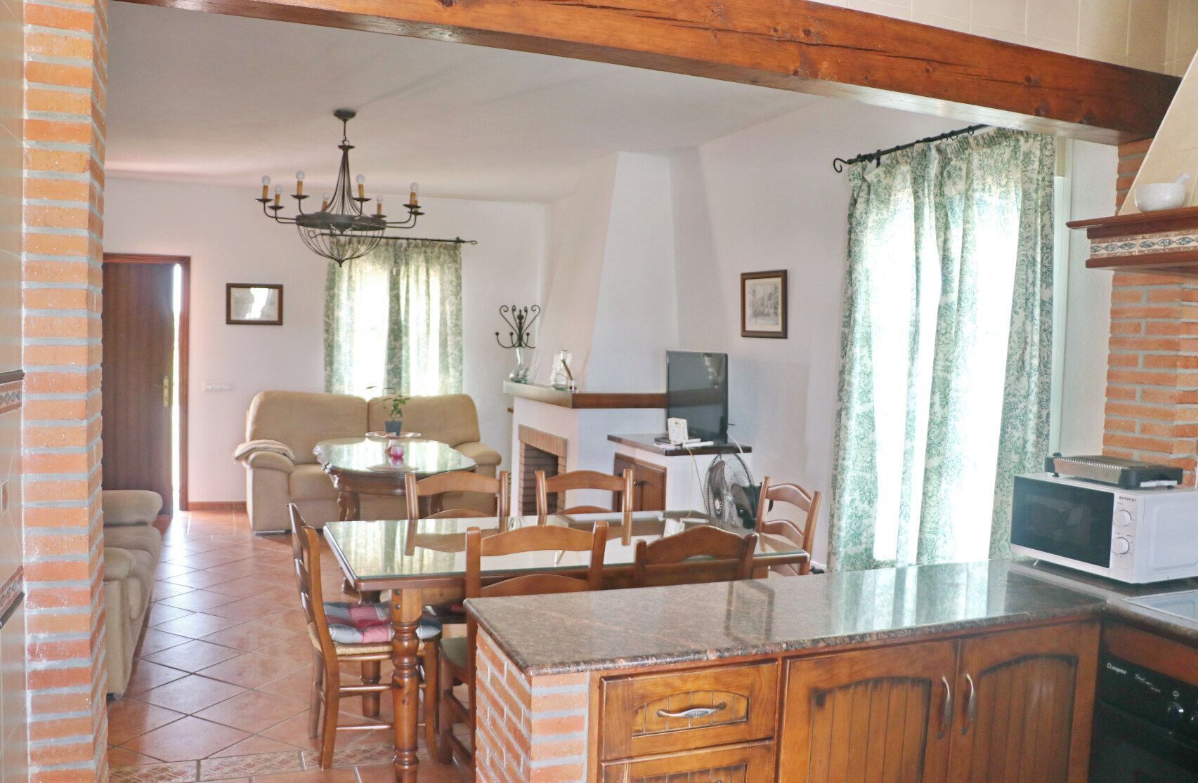 Ein Wohnzimmer mit einer Couch, einem Esstisch mit Stühlen, einem Fernseher und einem Kamin.