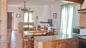 A living room with a sofa, a dining table with chairs, a TV, and a fireplace. - Casa Ana           . (Conil de la Frontera)
