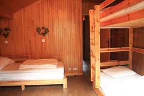 Une cabane en bois avec deux lits superposés, un plafond en bois et des lampes fixées au mur.