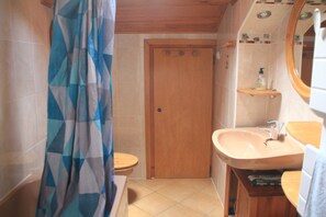 Une salle de bain avec une porte en bois, un lavabo et un rideau de douche.