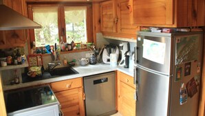 A kitchen with wooden cabinets, a dishwasher, a refrigerator, and various kitchen appliances. - Apartment With Parking in Chatel (Chatel)