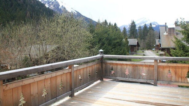A wooden deck with railings, surrounded by trees and a mountain backdrop. - Apartment With Parking in Chatel (Chatel)