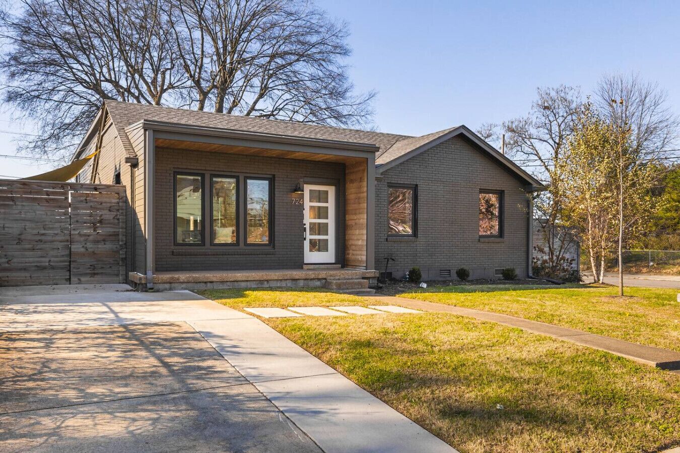 A modern two-story house with a brick exterior, large windows, and a well-maintained lawn.