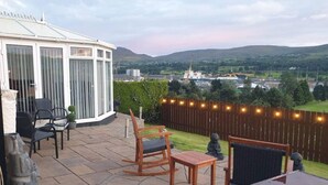 A patio with outdoor furniture, a conservatory, and a view of a river and hills. - Overlooking Carlingford Lough Modern and Spacious! (Warrenpoint)