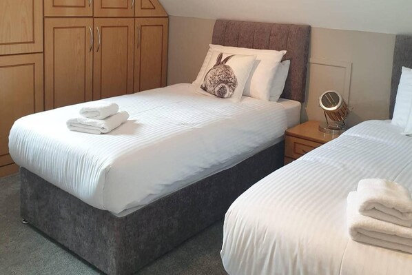 A hotel room with two beds, a wooden wardrobe, a bedside table with a lamp, and a mirror. - Overlooking Carlingford Lough Modern and Spacious! (Warrenpoint)