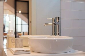 Ein Badezimmer mit einem weißen Waschbecken, einem Spiegel und einer Lotionflasche.