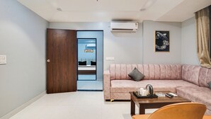 A modern living room with a sofa, a coffee table, and a door leading to a bathroom. - Hotel Grand Aana Inn (Jaipur)
