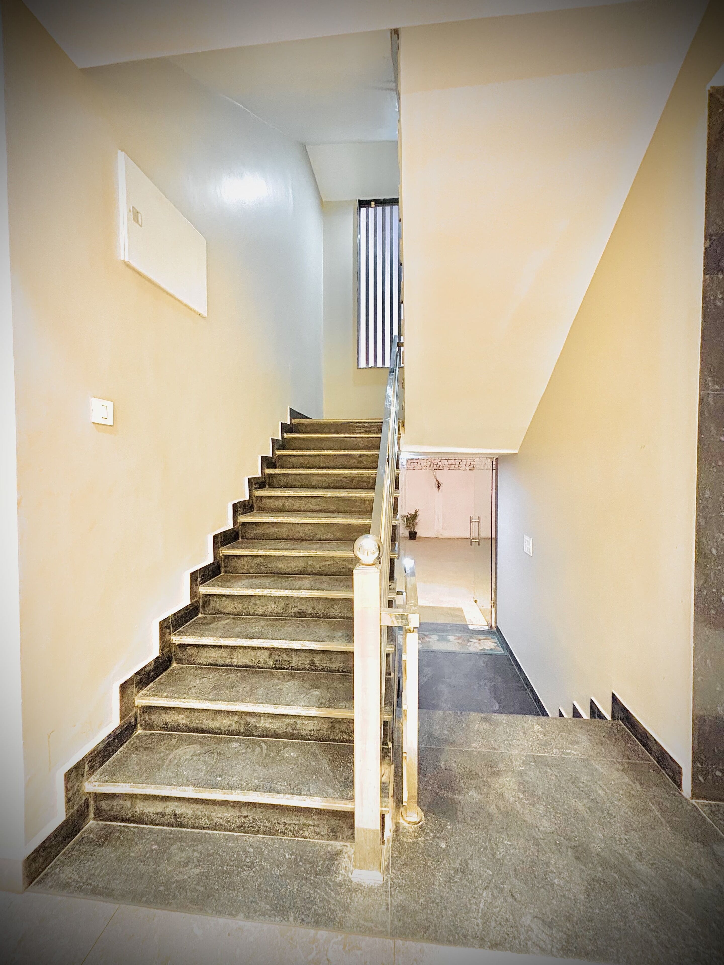 A staircase with a handrail, carpeted steps, and a light switch on the wall.