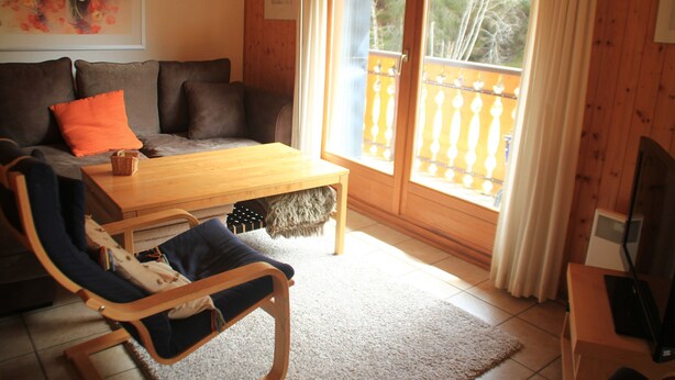 A cozy living room with a sofa, a wooden coffee table, a chair, and a balcony with a railing. - Myrtilles Mr27 Telecabine & Nature 6 Pers (Chatel)