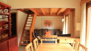 A wooden dining table with chairs, a staircase, a sofa, and a bookshelf in a cozy room. - Myrtilles Mr27 Telecabine & Nature 6 Pers (Chatel)