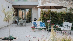 Ein Innenhof mit Sitzgelegenheiten im Freien, einem Grill und einem großen Sonnenschirm.