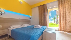 A hotel room with a bed, bedside tables, a nightstand, a window with curtains, and a view of palm trees. - Cozy studio with Sea View on the beach in Corfu (94X3+83V Kavos, Greece)