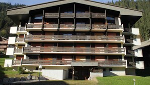 A multi-story hotel with balconies, a central entrance, and a mountainous backdrop. - Portes Du Soleil Psa47 Telecabine & Mountain 4 Per (Chatel)