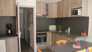 A compact kitchen with wooden cabinets, a microwave, a coffee maker, and a dining table with chairs. - Portes Du Soleil Psa47 Telecabine & Mountain 4 Per (Chatel)