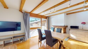 Une cuisine moderne avec des poutres en bois, un coin repas avec une table et des chaises en bois, un téléviseur et un four à micro-ondes.