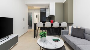 A modern living room with a flat-screen TV, a round coffee table with a plant, and a grey sofa. - Solange by halu! (Thessaloniki)